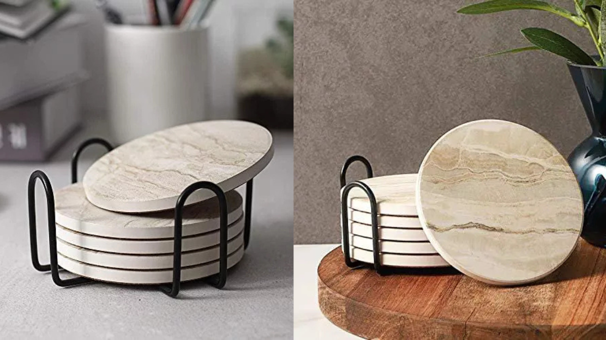A set of round beige marble coasters with subtle veining, neatly stacked in a black metal holder, displayed on a desk and a wooden surface.